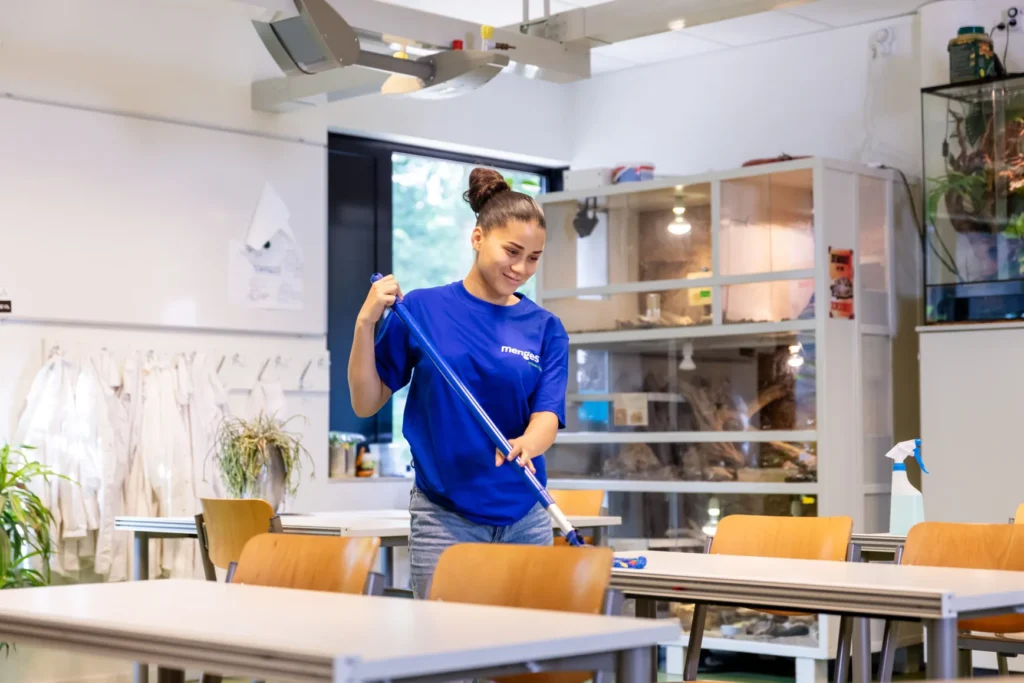 Medewerkster die schoolzaal schoonmaakt
