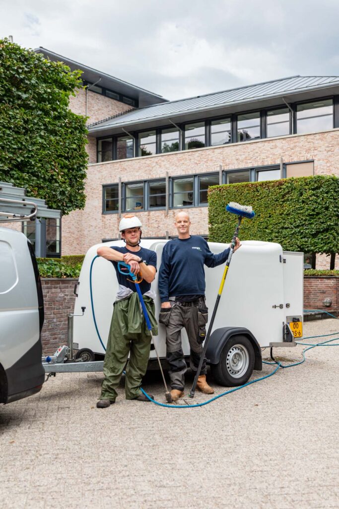 Medewerkers van Menges schoonmaak bij hun aanhanger met reinigingsmaterialen